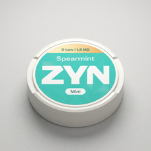 White ZYN Spearmint X-Low 1.5MG Mini Nicotine Pouches tin with teal and yellow label, featuring "Spearmint ZYN Mini" text.